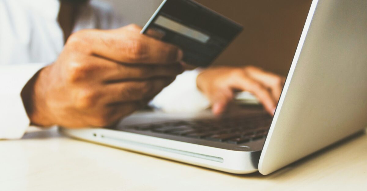 person using laptop computer holding card