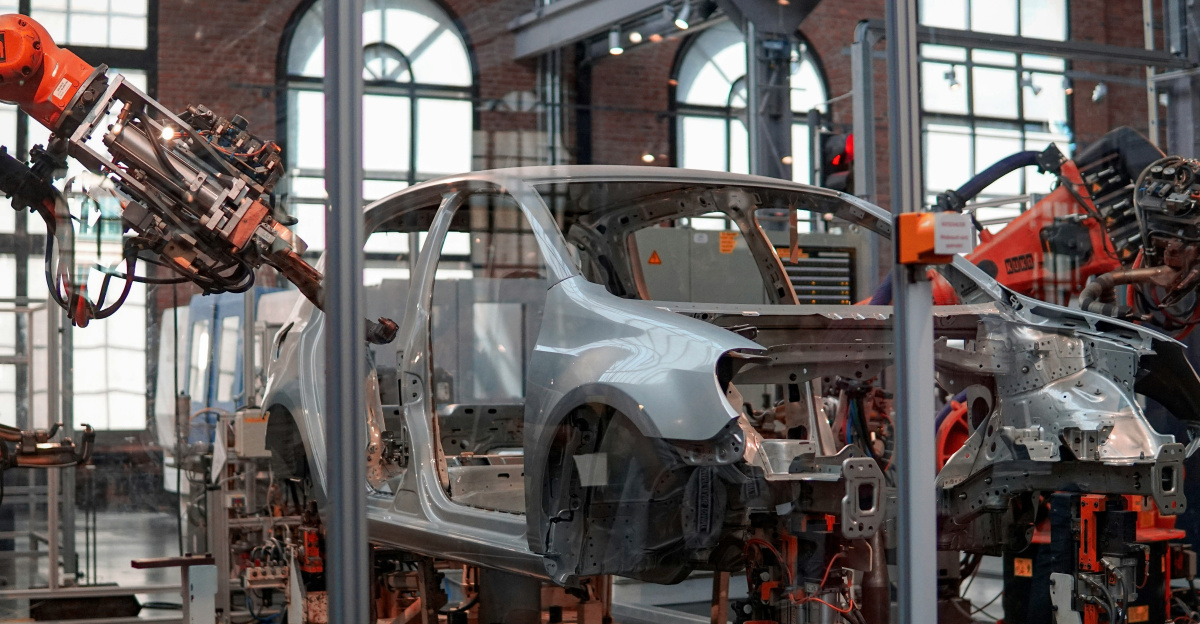 gray vehicle being fixed inside factory using robot machines