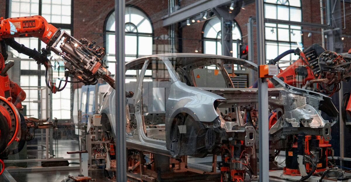 gray vehicle being fixed inside factory using robot machines