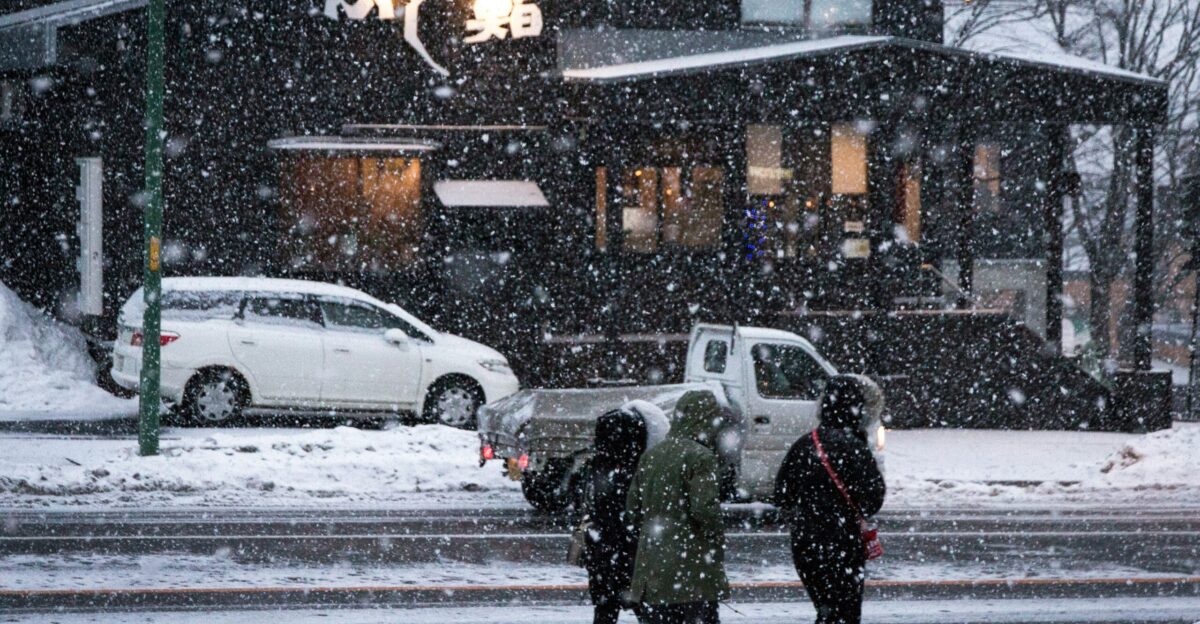 a group of people walking across a snow covered street
