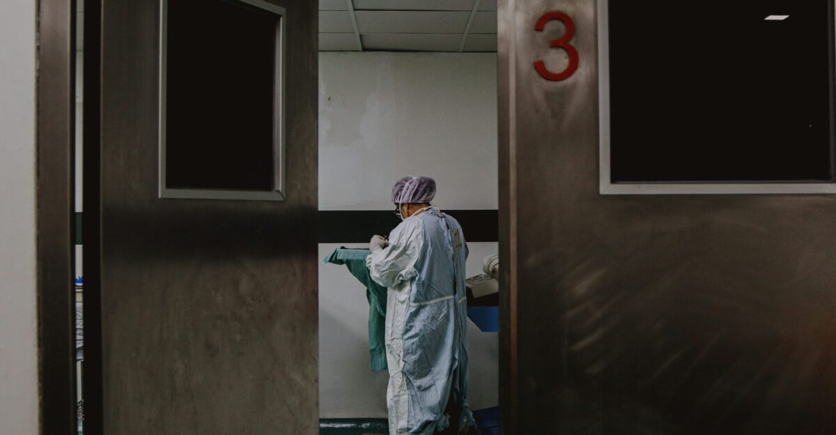man in white and blue robe standing near white wooden door