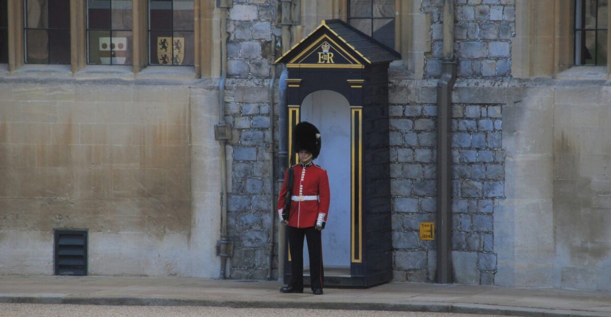 man in red and black uniform standing near gray concrete building during daytime