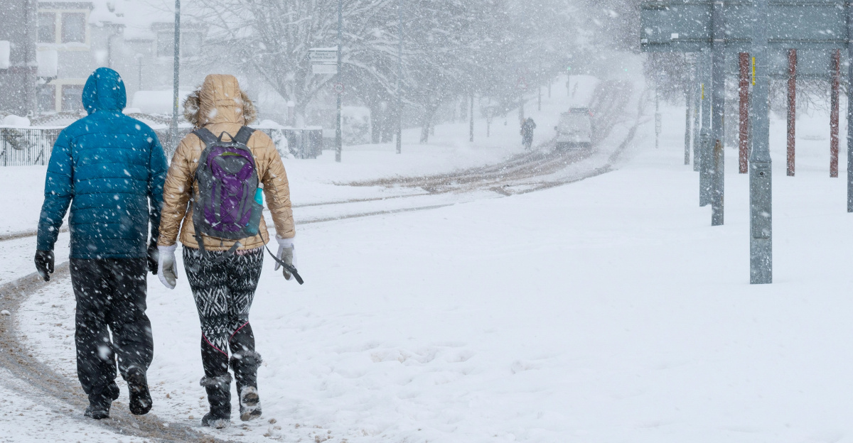 2 person walking on snow covered road during daytime