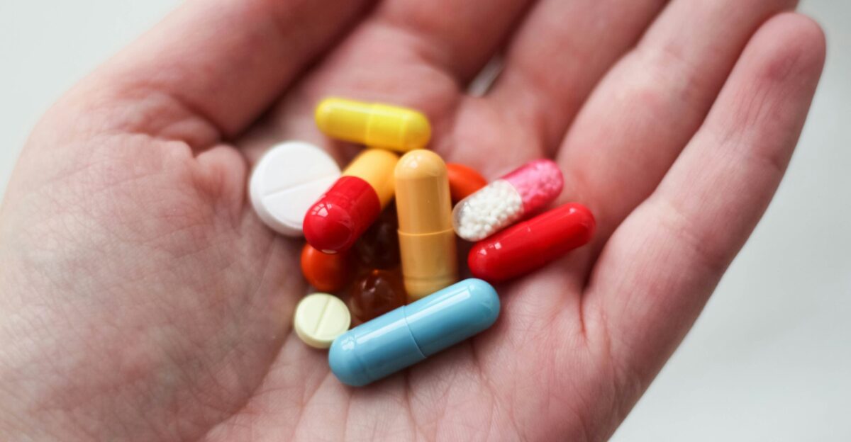 orange and white medication pill on persons hand