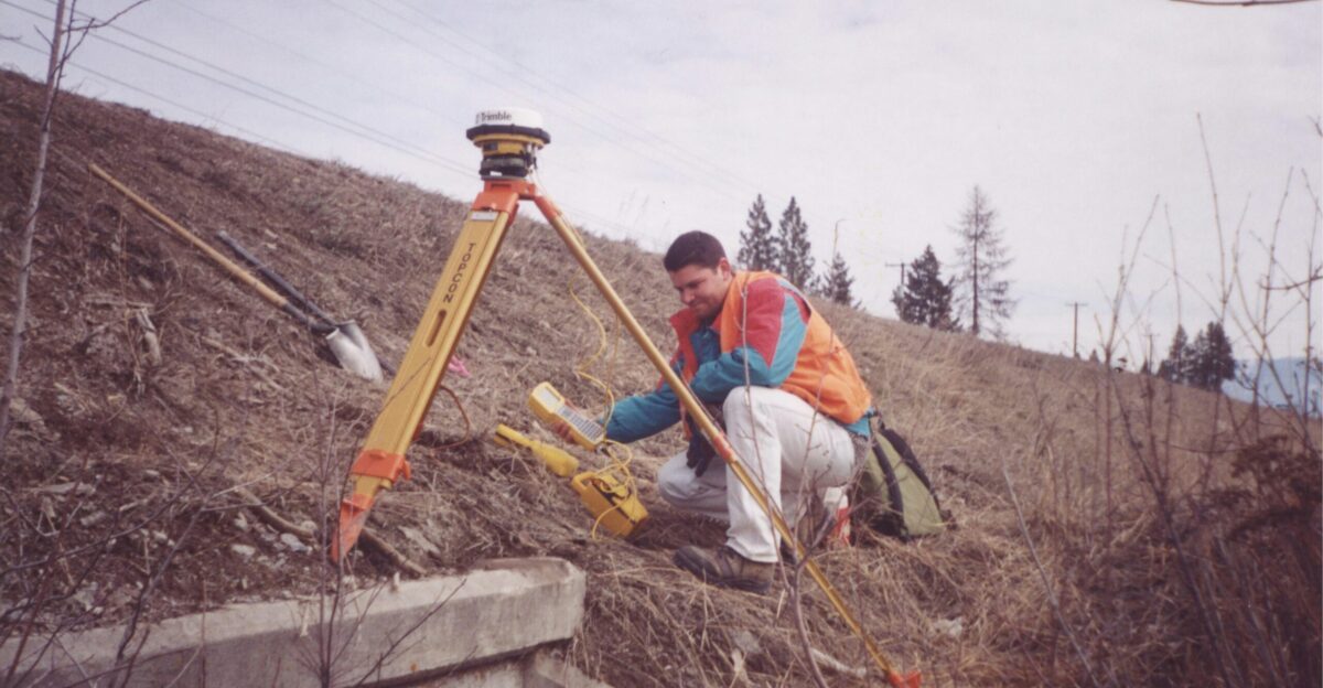 man in red jacket sitting on brown wooden ladder during daytime