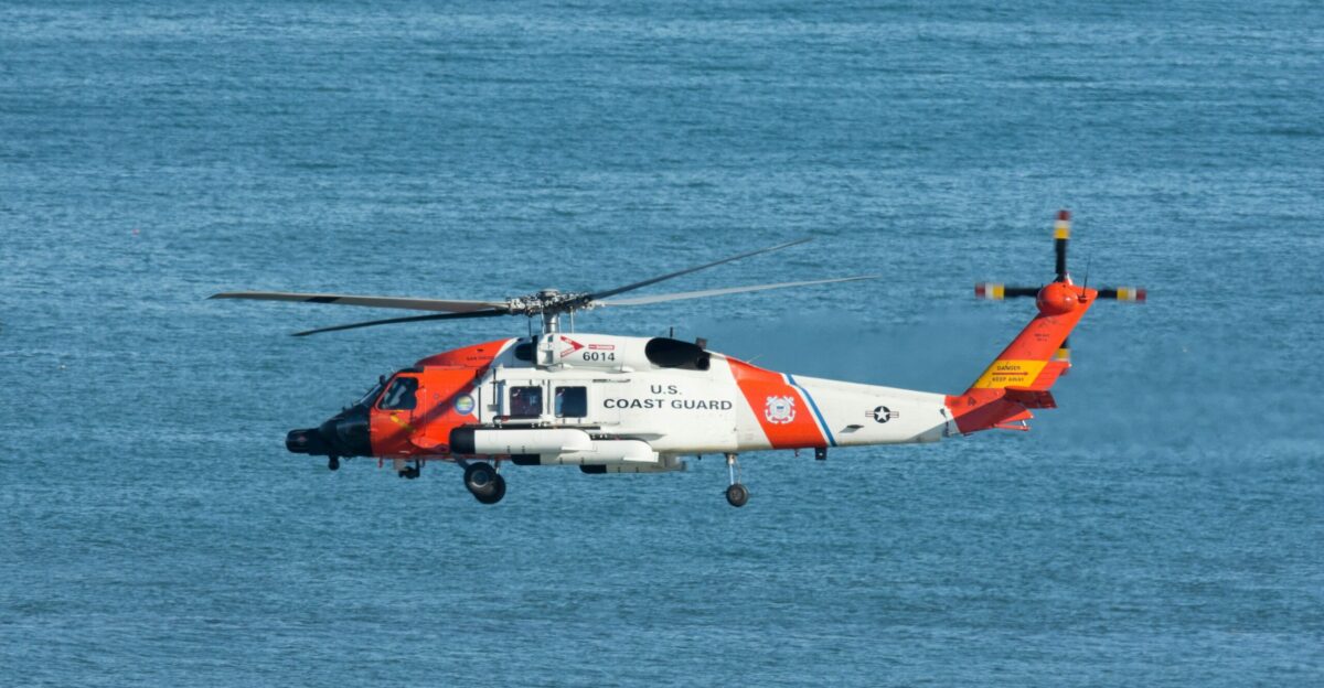 white and orange helicopter flying over the sea during daytime