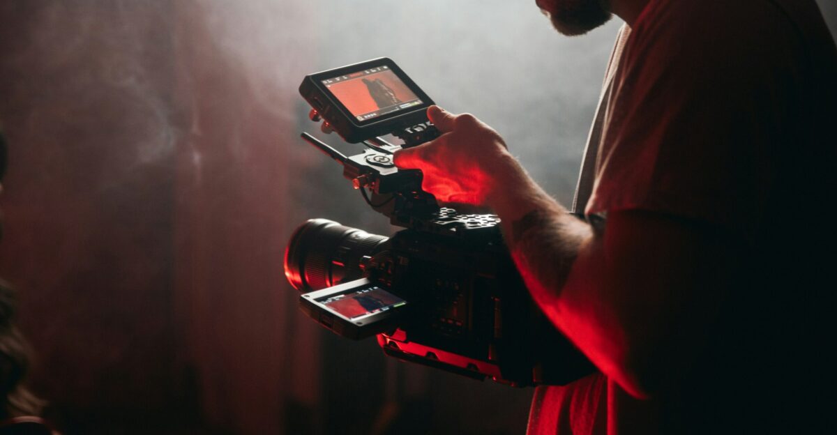 man in white t-shirt holding black video camera