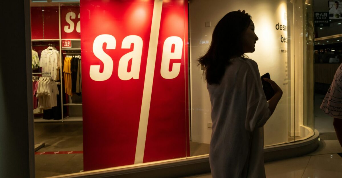 woman in gray coat standing near red and white stop sign