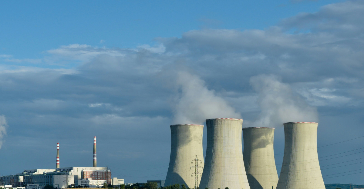 gray asphalt road between green grass field under blue sky during daytime