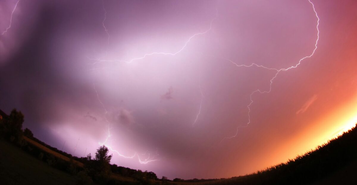 a purple and orange sky with a couple of lightnings