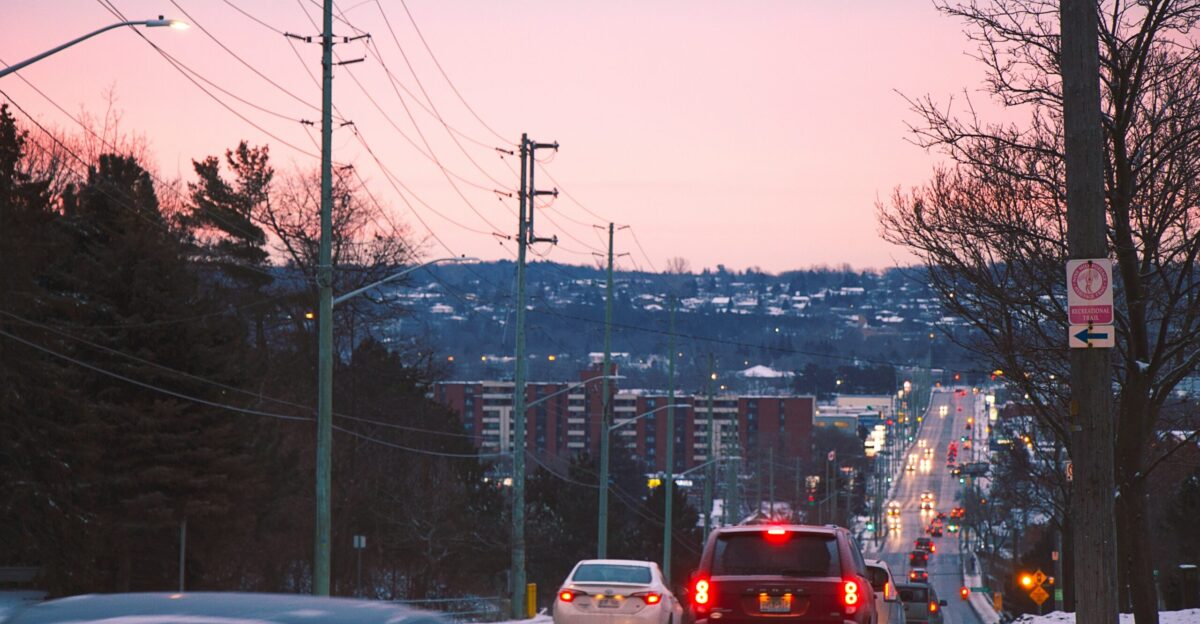 a city street with cars driving down it at dusk