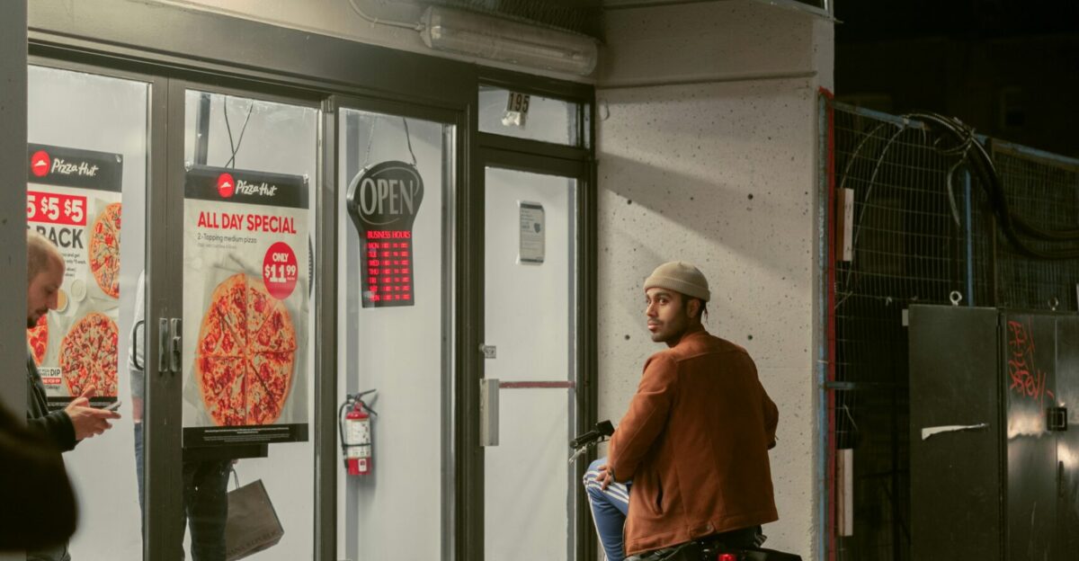a man riding a bike past a pizza hut