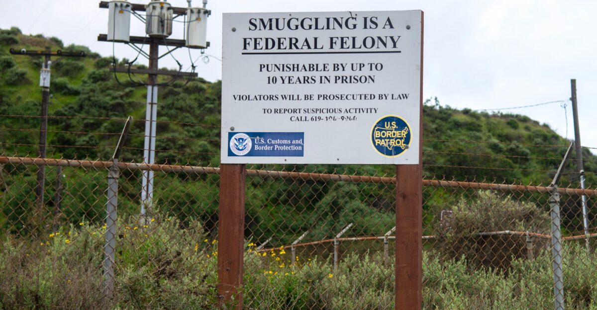 a sign is posted on a fence near a field