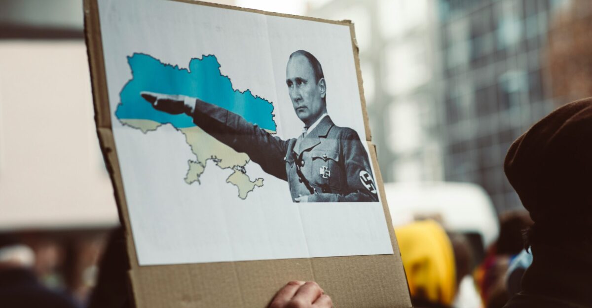 a person holding a sign with a picture of a man pointing a gun