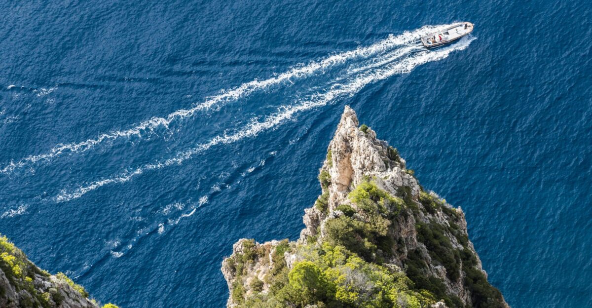 a boat traveling on the water near a mountain