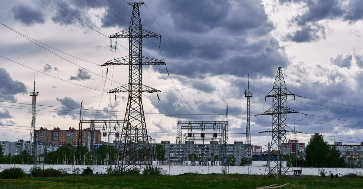 a field with power lines and buildings in the background