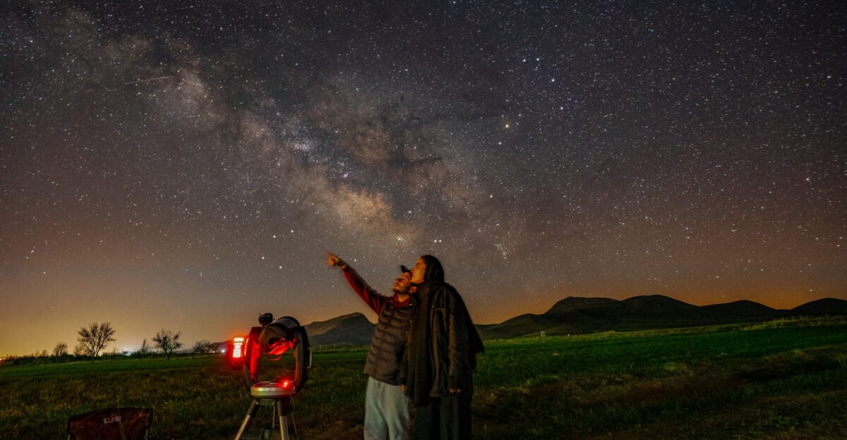 a man standing next to a telescope looking at the stars