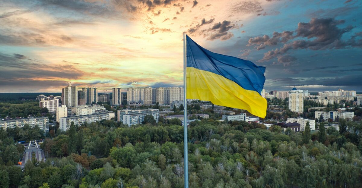 a flag on a pole with a city in the background