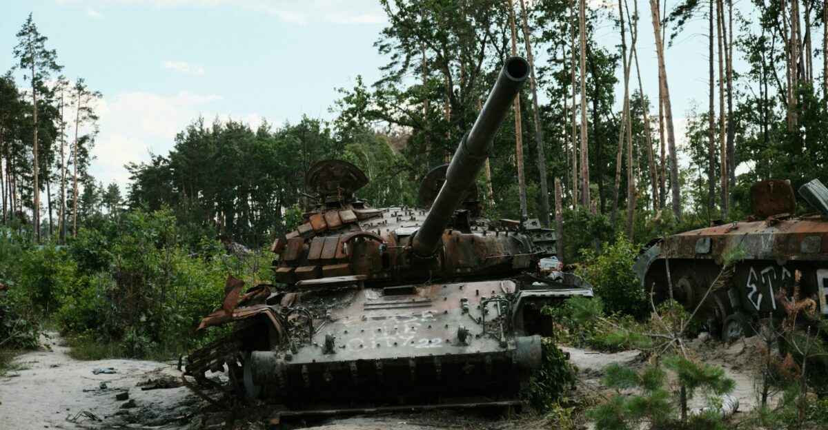 a rusted out tank sitting in the middle of a forest