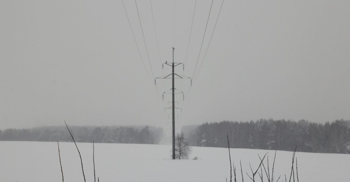 a snow covered field with power lines in the distance
