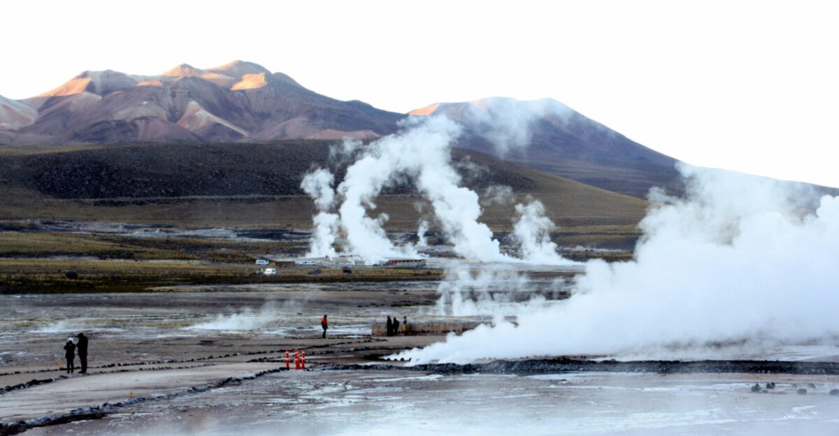 a group of people standing in front of a geyser
