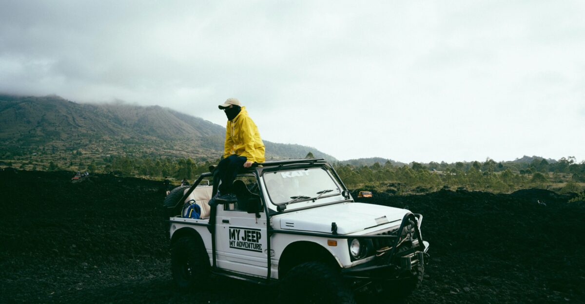 a man in a yellow jacket is sitting on top of a white truck