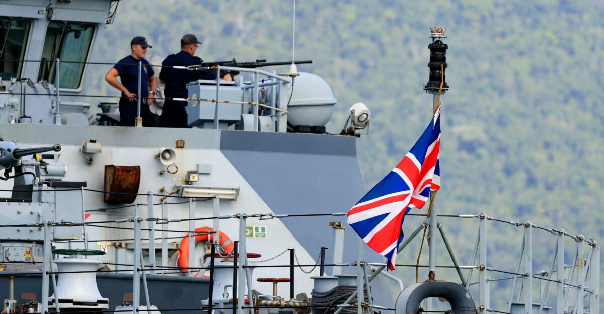 two men standing on top of a boat with a flag