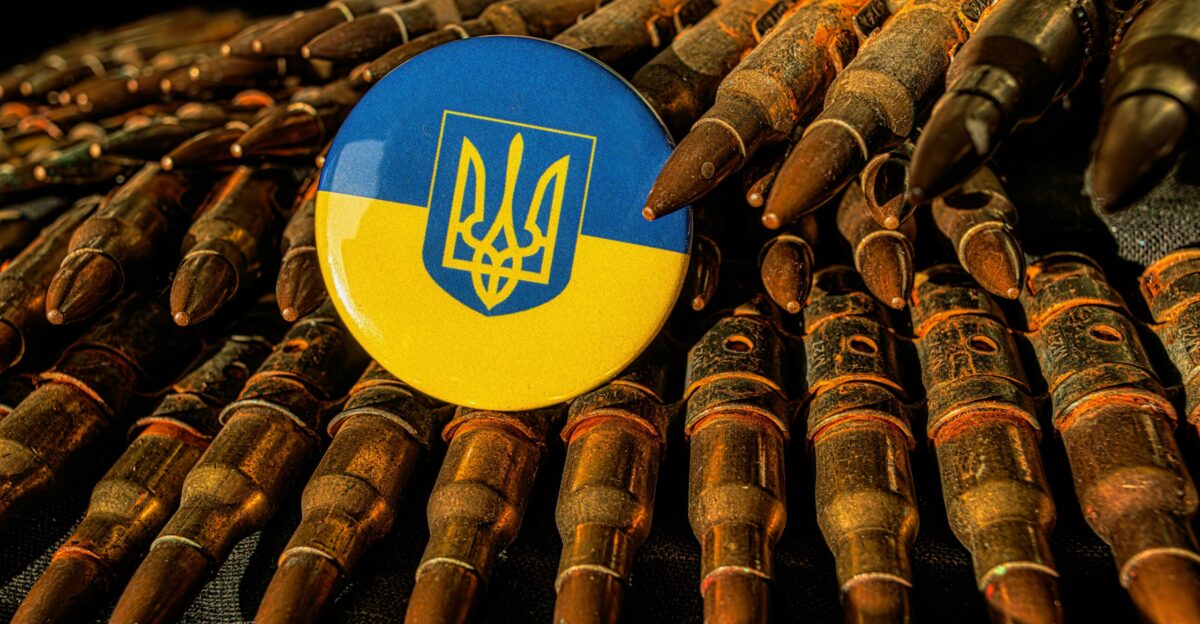 a blue and yellow button sitting on top of a pile of bullet shells