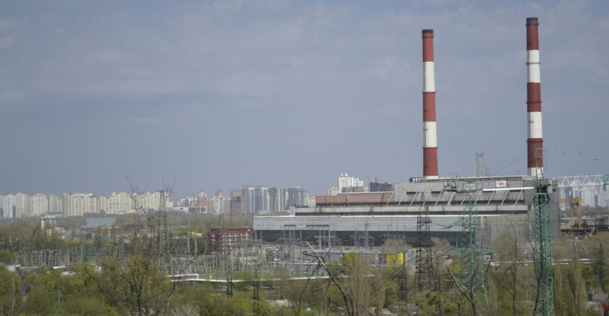 a view of a factory with smoke stacks in the background