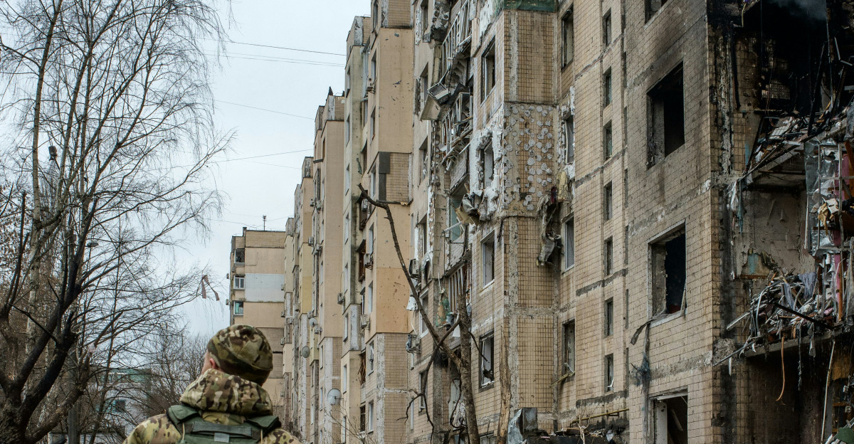 a man in camouflage walking through a destroyed building
