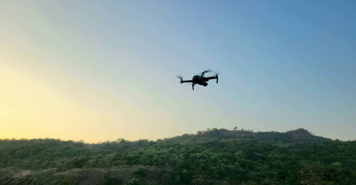 a small plane flying over a lush green hillside