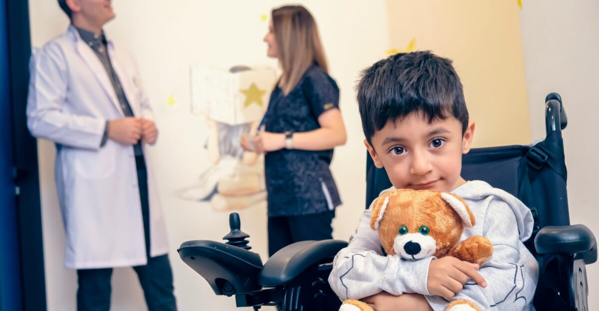 a boy in a wheelchair holding a teddy bear