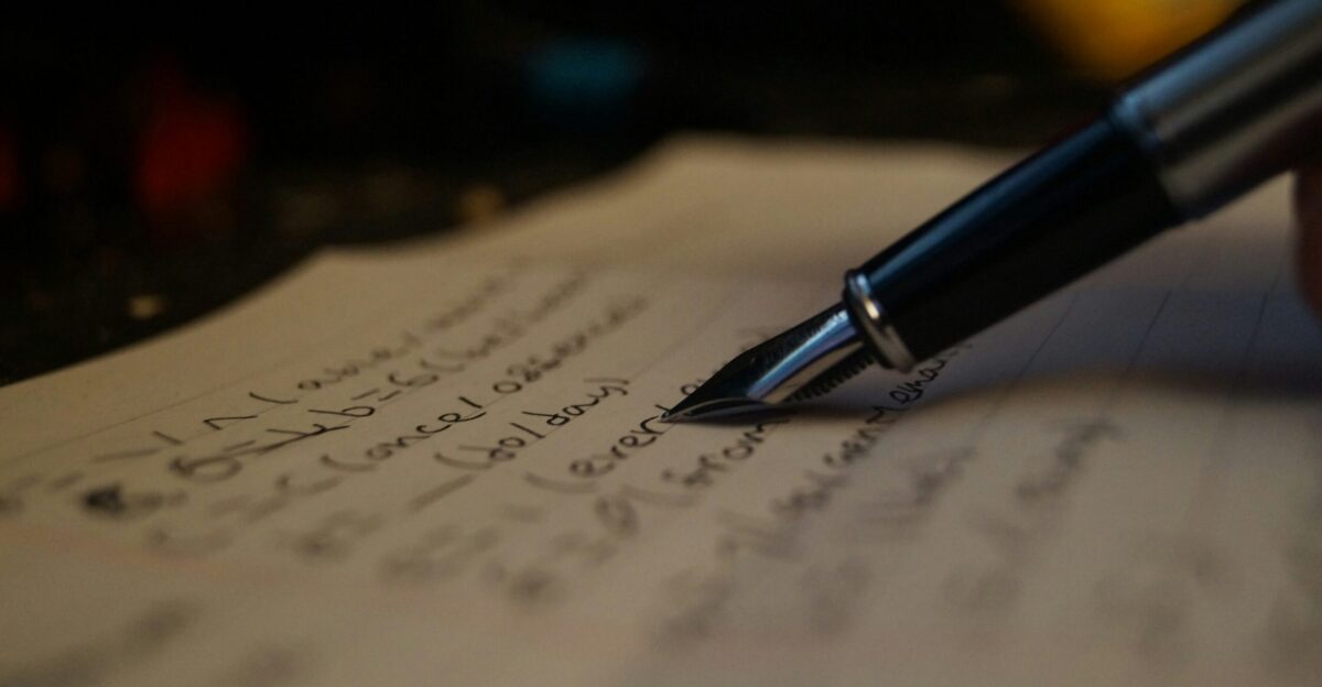 a person writing on a piece of paper with a pen