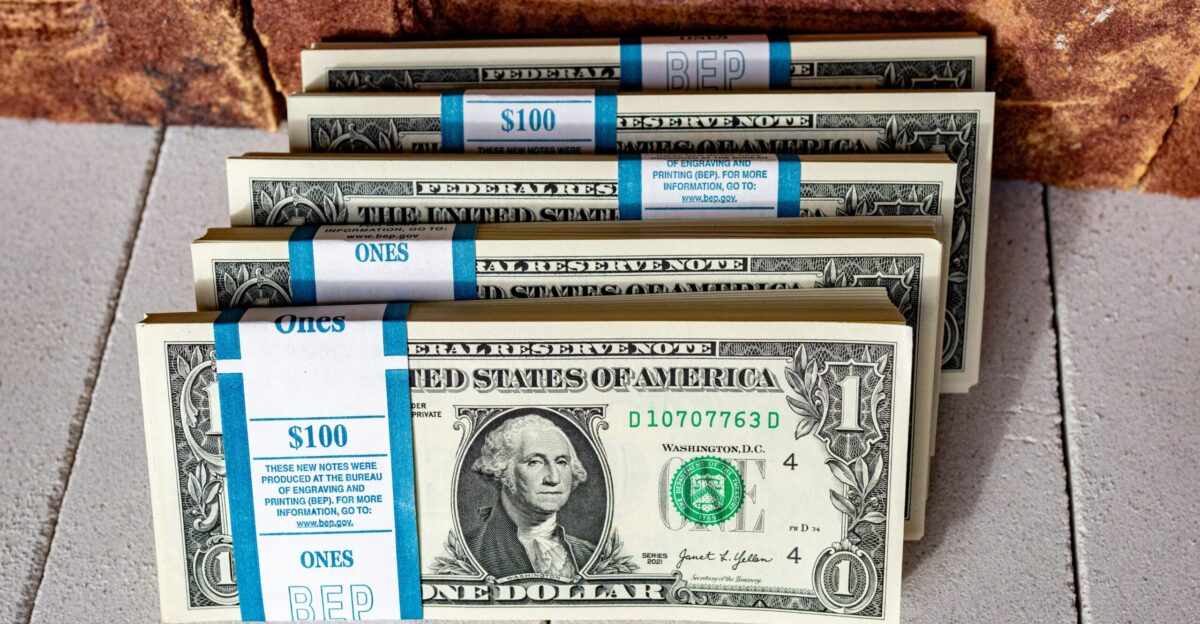 three stacks of one hundred dollar bills on a tile floor