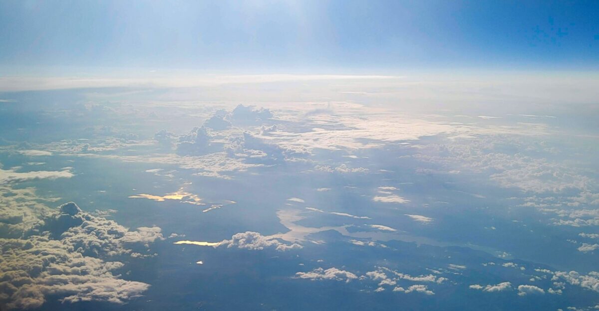 The sun is shining over the clouds in the sky