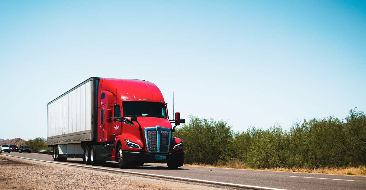 A red semi truck driving down a country road