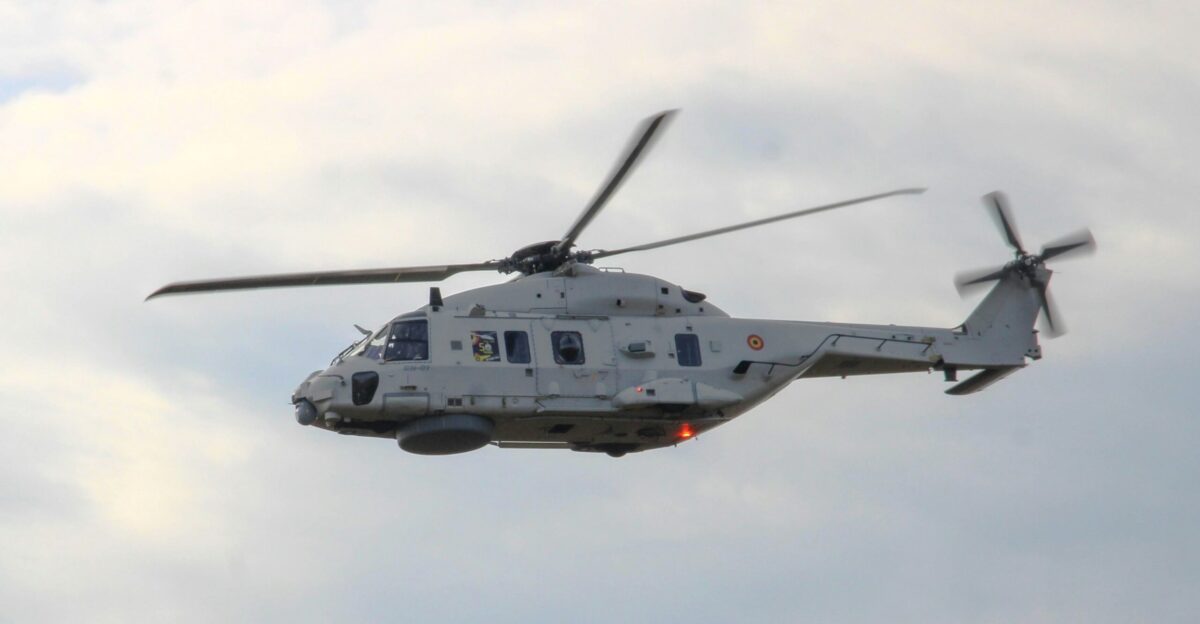 A helicopter flying through a cloudy blue sky