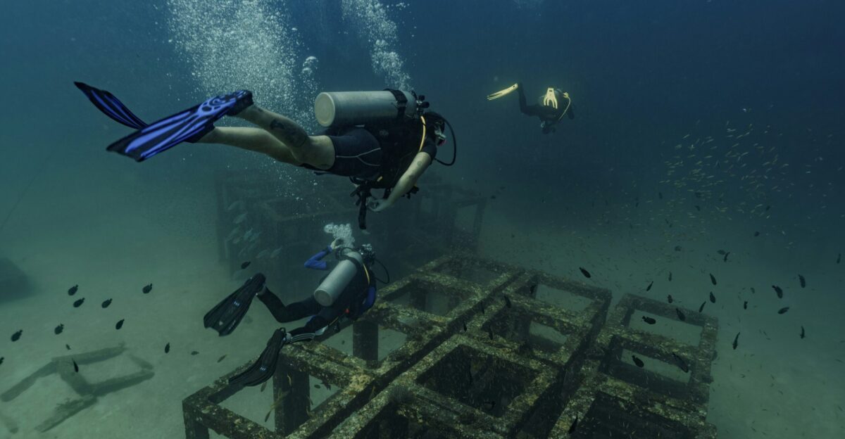 Scuba divers explore underwater structures with bubbles