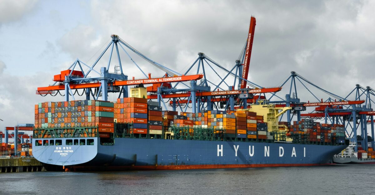 A hyundai container ship is docked at a port