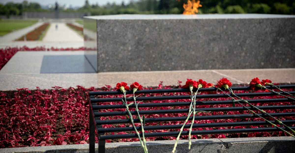 Red flowers lay before a memorial with eternal flame