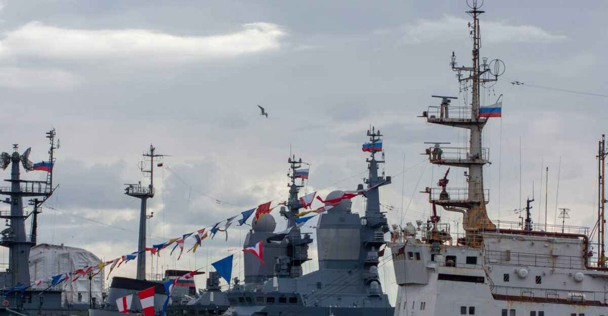 Several naval ships docked under a cloudy sky