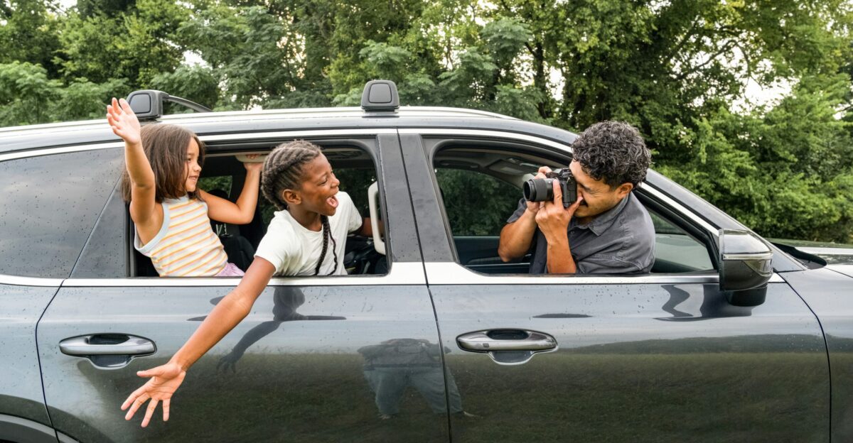 Man photographs children leaning out of car window