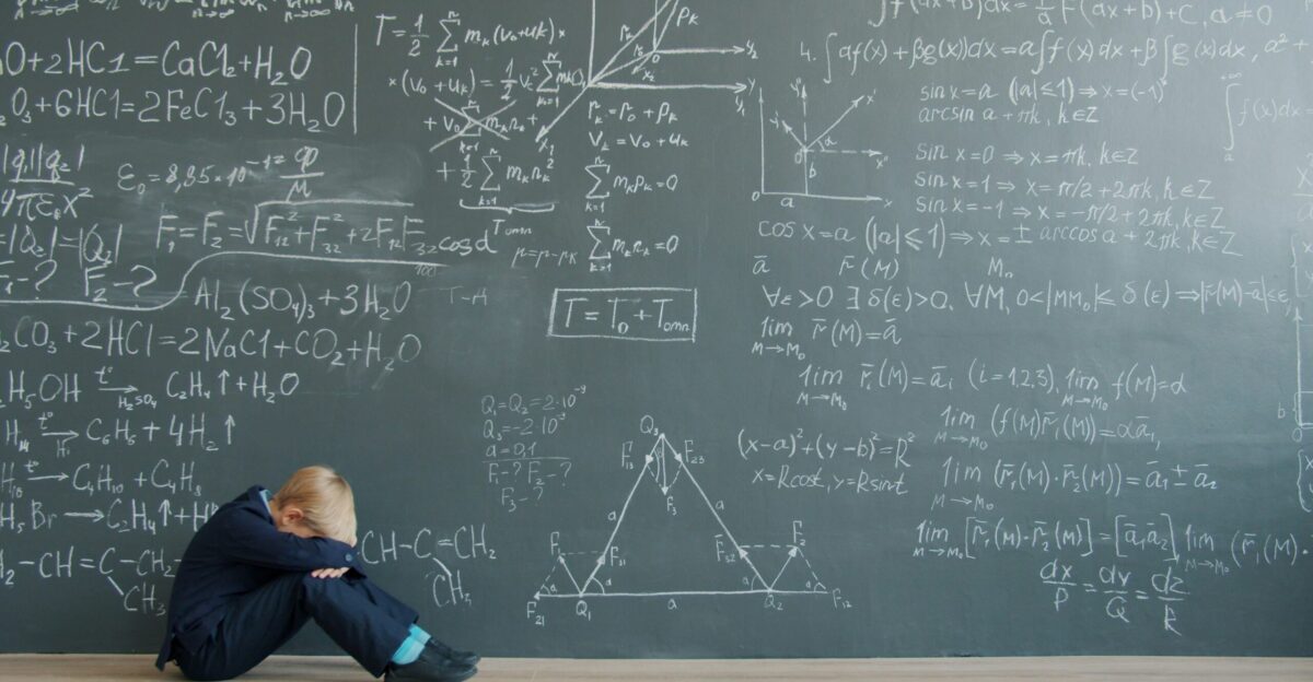 Student sits by blackboard covered in math equations