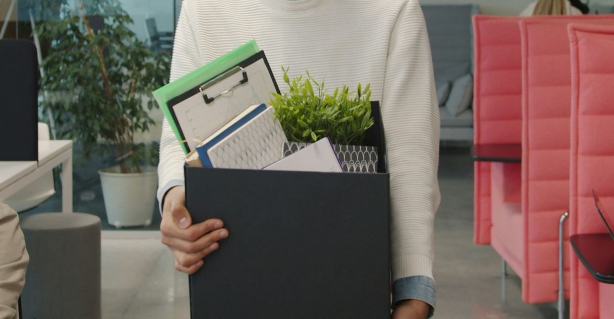 Man carrying box of belongings in modern office