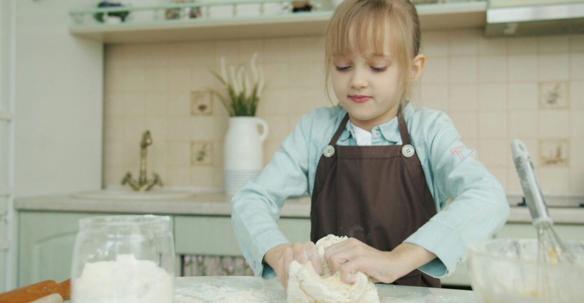 Young girl kneading dough in a kitchen