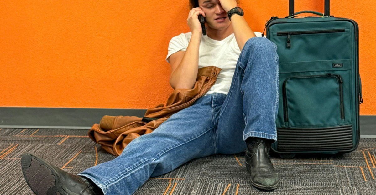 Man sitting on floor with suitcase looking distressed