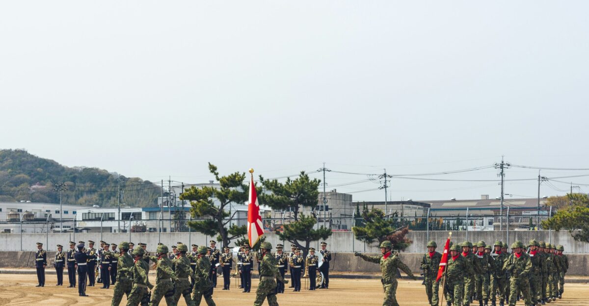 Soldiers in formation marching with flags on parade ground