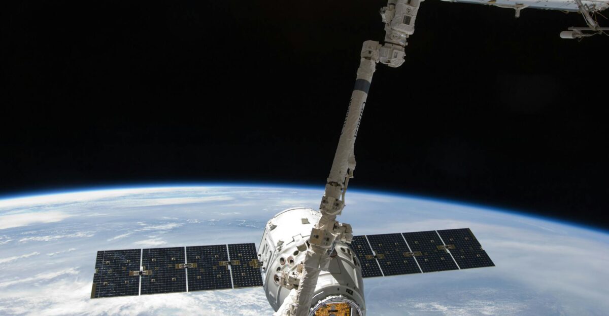 View of a spacecraft docked at the ISS above Earth with visible solar panels