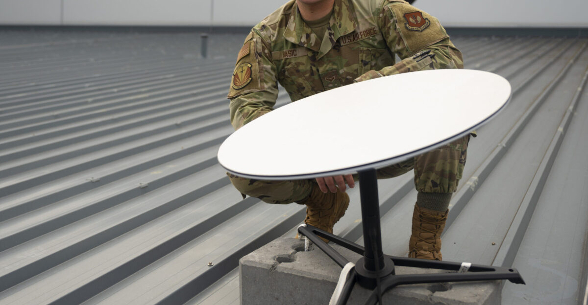 U S Air Force Airman 1st Class Alexander Basic 86th Communications Squadron network infrastructure technician kneels behind a Starlink terminal at Ramstein Air Base Germany Sept 21 2021 Ramstein received 15 terminals for use in the test phase as well as support of evacuation operations U S Air Force photo by Senior Airman Thomas Karol