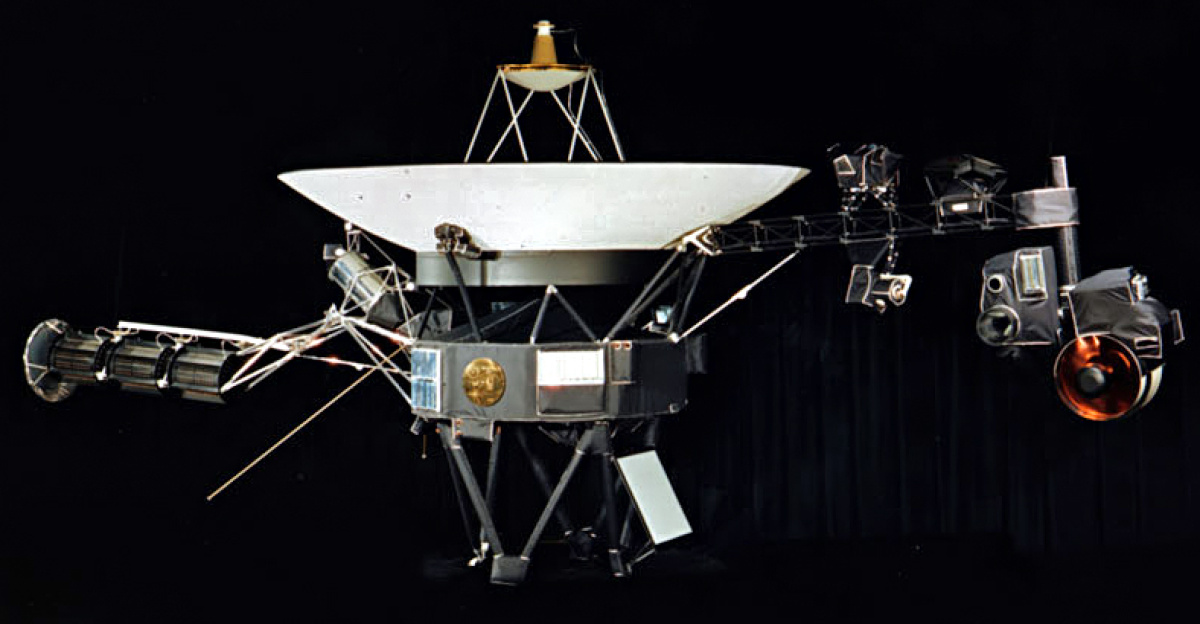 NASA photograph of one of the two identical Voyager space probes <a href="//commons.wikimedia.org/wiki/Voyager_1" title="Voyager 1">Voyager 1</a> and <a href="//commons.wikimedia.org/wiki/Voyager_2" title="Voyager 2">Voyager 2</a> launched in 1977.
<p>The 3.7 metre diameter high-gain antenna (HGA) is attached to the hollow ten-sided polygonal body housing the electronics, here seen in profile. The <a href="//commons.wikimedia.org/wiki/Category:Voyager_Golden_Record" title="Category:Voyager Golden Record">Voyager Golden Record</a> is attached to one of the bus sides.
</p><p>The angled square panel below is the optical calibration target and excess heat radiator.
</p><p>The three <a href="//commons.wikimedia.org/wiki/Category:Radioisotope_thermoelectric_generators" title="Category:Radioisotope thermoelectric generators">radioisotope thermoelectric generators</a> (RTGs) are mounted end-to-end on the left-extending boom. One of the two planetary radio and plasma wave antenna extends diagonally left and down, the other extends to the rear, mostly hidden here. The compact structure between the RTGs and the HGA are the high-field and low-field magnetometers (MAG) in their stowed state; after launch an Astromast boom extended to 13 metres to distance the low-field magnetometers.
</p><p>The instrument boom extending to the right holds, from left to right: the cosmic ray subsystem (CRS) above and Low-Energy Charged Particle (LECP) detector below; the Plasma Spectrometer (PLS) above; and the scan platform that rotates about a vertical axis.
</p><p>The scan platform comprises: the Infrared Interferometer Spectrometer (IRIS) (largest camera at right); the Ultraviolet Spectrometer (UVS) to the right of the UVS; the two Imaging Science Subsystem (ISS) vidicon cameras to the left of the UVS; and the Photopolarimeter System (PPS) barely visible under the ISS.
</p>
Suggested for English <a href="https://en.wikipedia.org/wiki/Wikipedia:alternative_text_for_images" class="extiw" title="en:Wikipedia:alternative text for images">Wikipedia:alternative text for images</a>: A space probe with squat cylindrical body topped by a large parabolic radio antenna dish pointing upwards, a three-element radioisotope thermoelectric generator on a boom extending left, and scientific instruments on a boom extending right. A golden disk is fixed to the body.